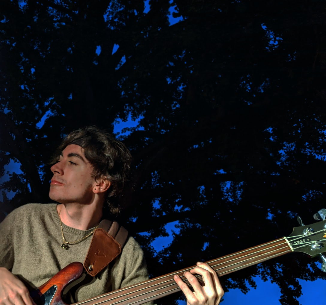  Rocco playing a fretless bass on a blue sky night